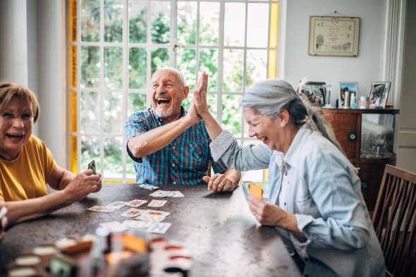 Senior people playing cards in nursing home Ältere Menschen sitzen am Tisch und spielen Karten