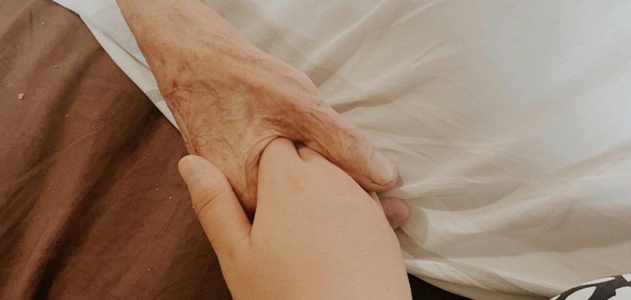 Eine Person hält die Hand eines alten Menschen Eine Person hält die Hand eines alten Menschen