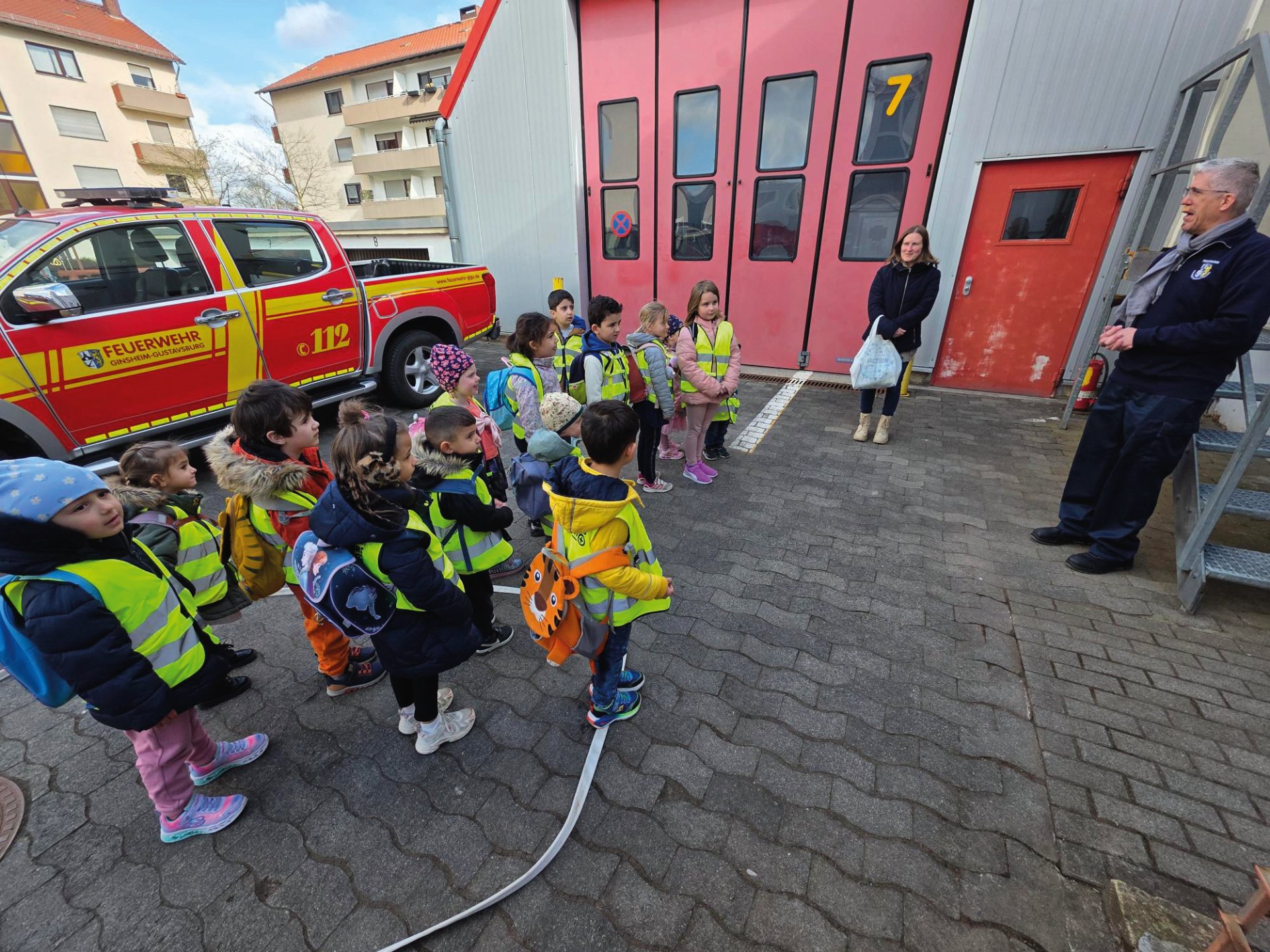 Frau Kollross (Erzieherin der Lukas-Gruppe) und Uwe Waldherr von der Feuerwehr Gustavsburg mit den gebannt lauschenden Kita-Kindern der Kita Lummerland Frau Kollross (Erzieherin der Lukas-Gruppe) und Uwe Waldherr von der Feuerwehr Gustavsburg mit den gebannt lauschenden Kita-Kindern der Kita Lummerland