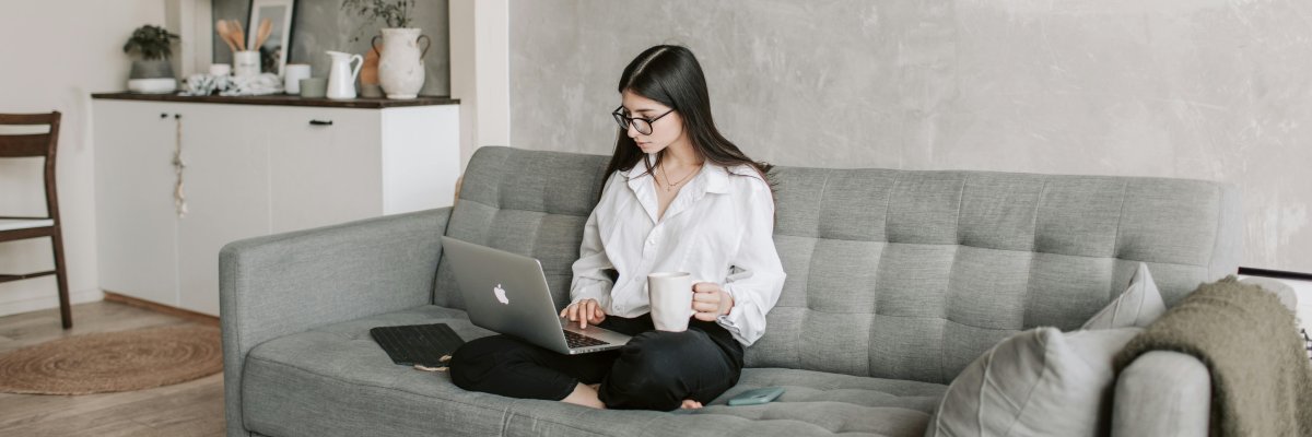 Frau sitzt mit Laptop auf einem Sofa