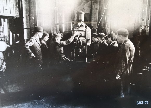 Der Umgang mit einer Maschine wird eingeübt. Der Dolmetscher der M.A.N., Theodor Reé (mit Hut), hilft mit Übersetzungen der Erklärungen.